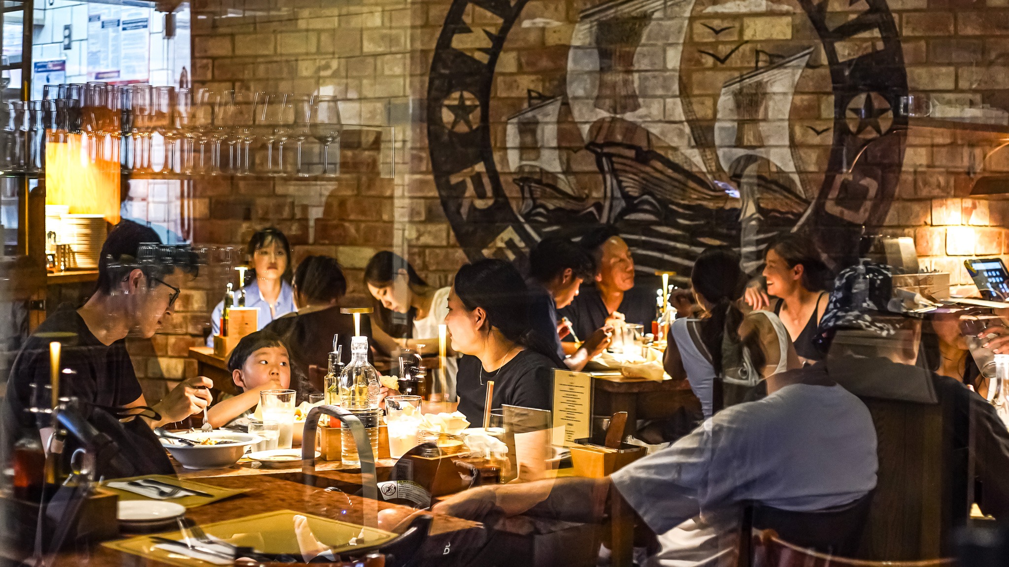 The warm, candlelit dining room at Maccheroni Republic, beneath its glowing emblem